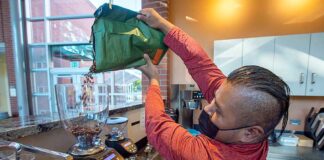 Tigard small business program boosts new café El Cuadrilátero Israel Martinez pours fresh coffee beans into a grinder.
