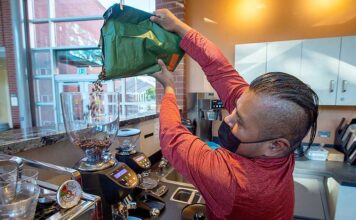 Tigard small business program boosts new café El Cuadrilátero Israel Martinez pours fresh coffee beans into a grinder.