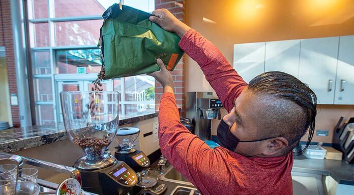 Tigard small business program boosts new café El Cuadrilátero Israel Martinez pours fresh coffee beans into a grinder.