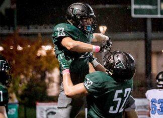 Rain or shine, Tigard football takes the field Junior Reese Hare (52) lifts up Henry Masters (23) in celebration.