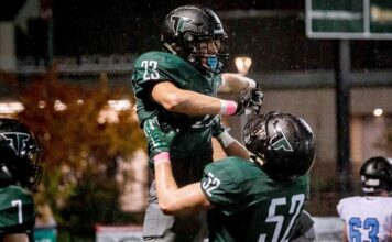 Rain or shine, Tigard football takes the field Junior Reese Hare (52) lifts up Henry Masters (23) in celebration.