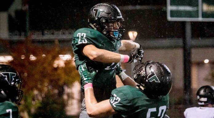 Rain or shine, Tigard football takes the field Junior Reese Hare (52) lifts up Henry Masters (23) in celebration.