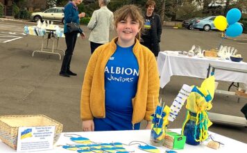 Rise Church Bake Sale raises $4,400 for Ukrainian Relief Frances stump stands behind an assortment of oranments, key chains, and necklaces she made and contributed for the fundraiser.