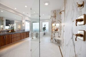 The 1999 remodeled primary bathroom features a luxurious walk-in shower, dramatic floor-to-ceiling porcelain slabs on the wall, and a freestanding bathtub to soak in the views. 