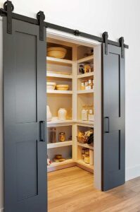 This modern farmhouse pantry is equal parts functional and beautiful. The painted barn doors keep the space tidy, while open shelves show off kitchen cabinet organization.