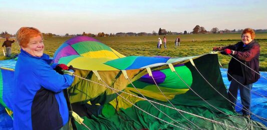 Longtime balloon crew members Marilyn Barnhart (L) and Edie Stoaks hold the opening of a hot air balloon to assist in its inflation. Both women have volunteered on crew since the 1990s.