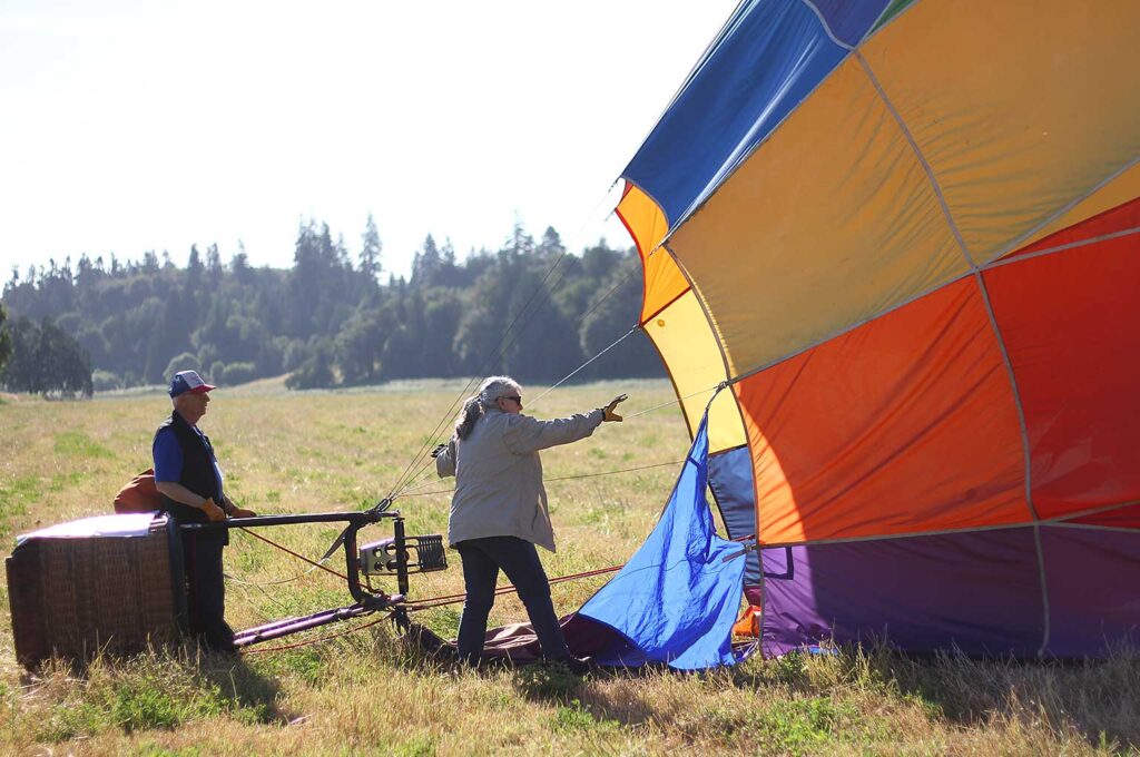 Pilot Dale Justice and Susan Plummer, part of his crew, work on deflating his balloon after an early morning flight Friday morning.JPG