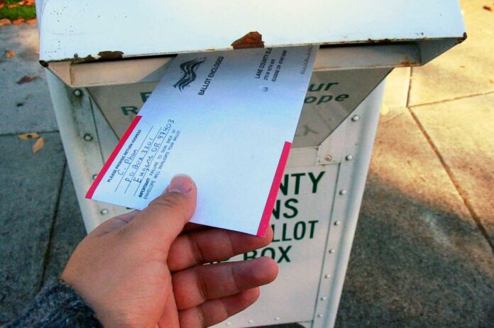 Oregon_ballot_return_box-WEB An Oregonian slides their completed ballot into a secure return box, a fixture of the state's all-mail voting system for over 25 years.