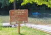 Council ‘triages’ Tigard parks’ looming shortfall Sign for the Cook Family Park boat launch on the Tualatin River with a kayaker in the background.