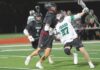 Tigard lacrosse teams see growth despite records A Tigers lacrosse player in a white jersey (number 27) maneuvers past two Tualatin defenders in black jerseys during a night game on a turf field.