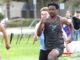 Tigard track hits ground running to start spring Tigard track athlete Marcus Burton, wearing a grey tiger-striped jersey, sprinting at full speed during a 100-meter dash on an outdoor track.