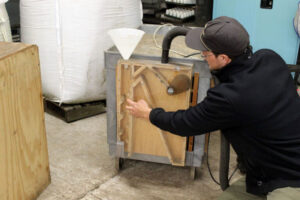 Tillamook Estuaries Partnership plant material program manager Asa Skinner shows off an air separator machine a youth at Camp Tillamook made during his woodshop courses to help nursery staff separate seeds from chaff.