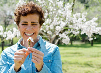 Histamine and Seasonal Allergies: A woman with a flower and a blooming tree in the background