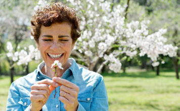 Histamine and Seasonal Allergies: A woman with a flower and a blooming tree in the background