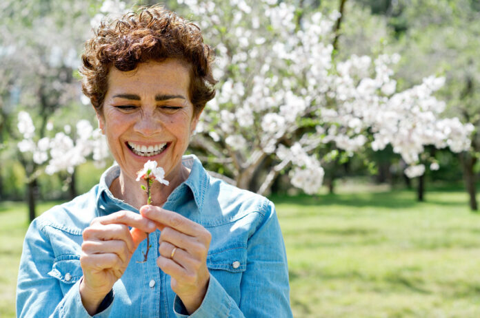 A woman with a flower and a blooming tree in the background