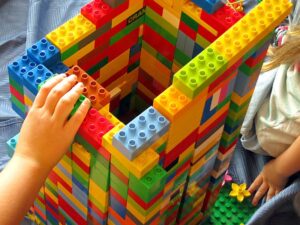 Two children building a tower with various colored legos.