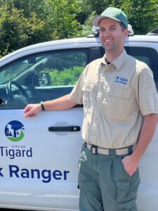 Jordan Porter, park ranger for the city of Tigard, stands alongside his Park Ranger truck, a Ford Ranger, just outside the wooded area of Dirksen Park. 
