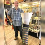 Tigard store channels gold-mining magic Dan Rouse, owner of Prospector's Treasure Trove, stands with a sluice box in front of a display case showing gold-mining artifacts in his store.