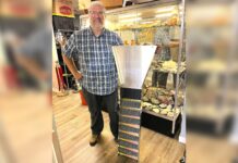 Tigard store channels gold-mining magic Dan Rouse, owner of Prospector's Treasure Trove, stands with a sluice box in front of a display case showing gold-mining artifacts in his store.