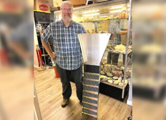 Tigard store channels gold-mining magic Dan Rouse, owner of Prospector's Treasure Trove, stands with a sluice box in front of a display case showing gold-mining artifacts in his store.