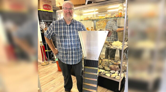 Tigard store channels gold-mining magic Dan Rouse, owner of Prospector's Treasure Trove, stands with a sluice box in front of a display case showing gold-mining artifacts in his store.