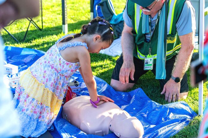 A child learning CPR at Tigard CERT Fair