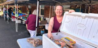 Food Bank Forges On, Even Without Permanent Location Tigard Community Food Project founder Amy Fierderowicz helps man the meat station while volunteers hand out groceries to people on Oct. 6.