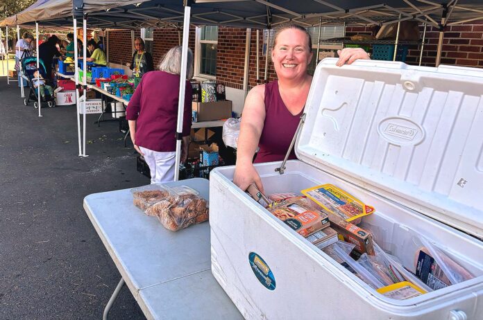 Tigard Community Food Project founder Amy Fierderowicz helps man the meat station while volunteers hand out groceries to people on Oct. 6.
